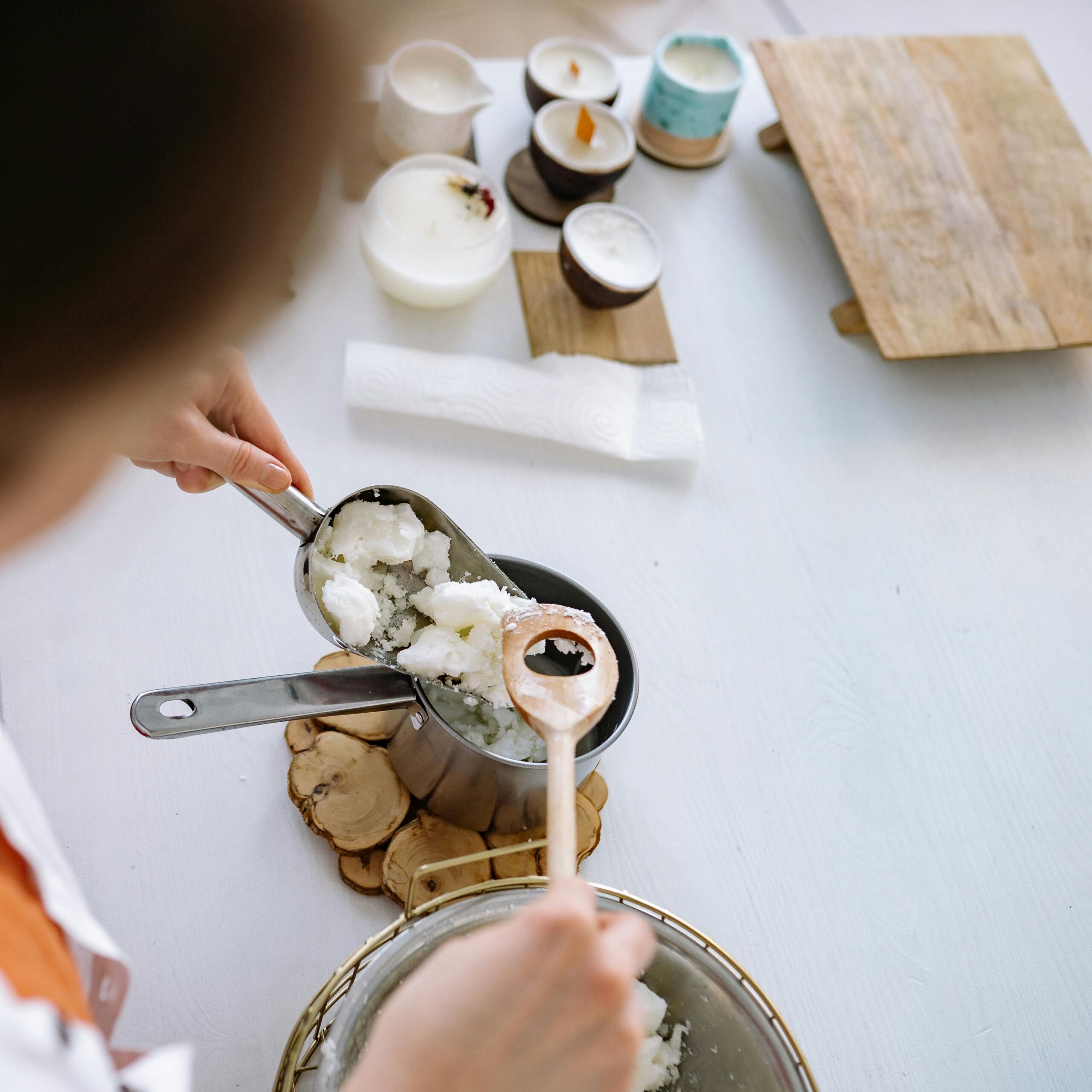 A person handcrafting candles using natural wax in a home workshop setting.